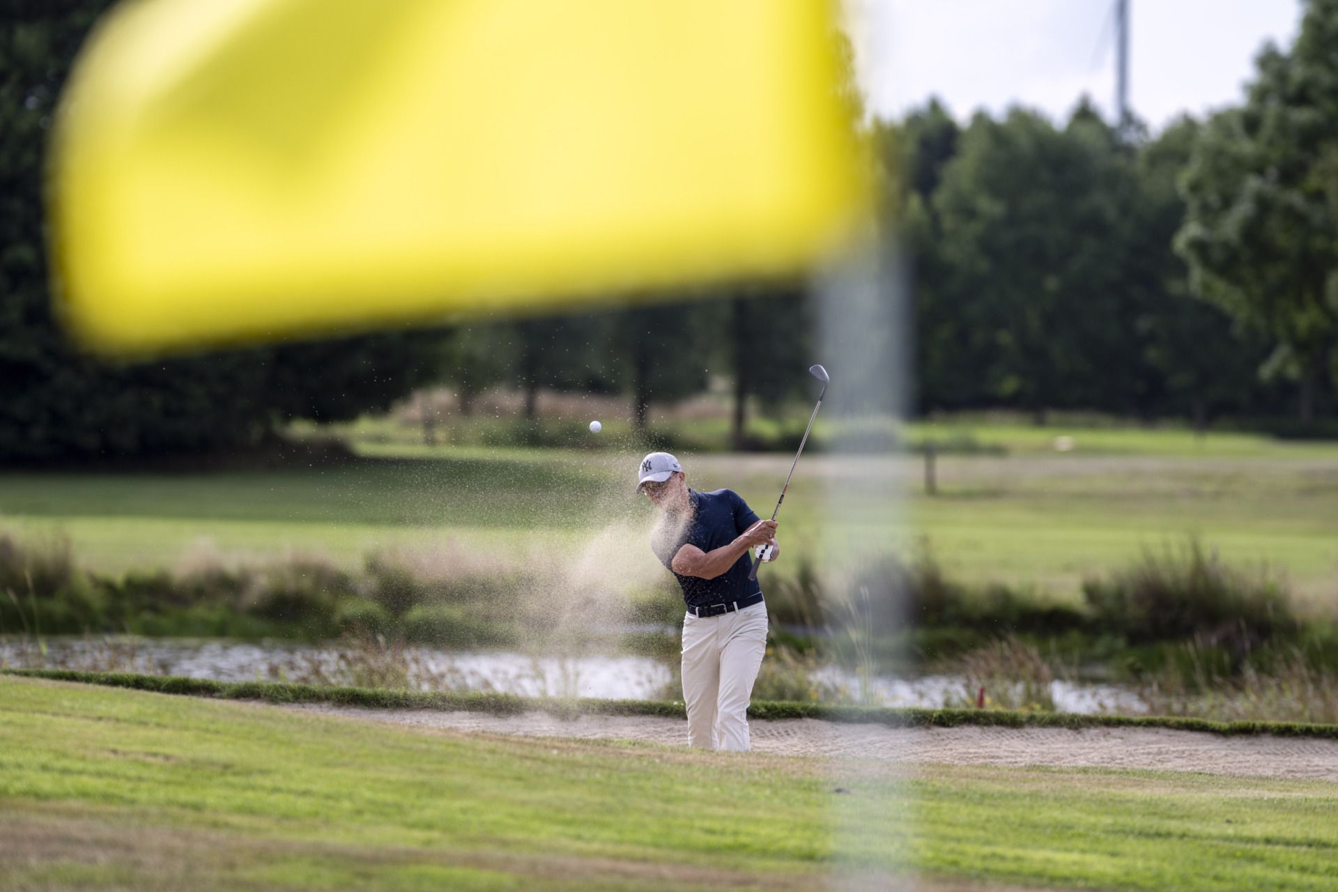 tehkat.unternehmensnachfolge dsc8295 Im Hintergrund ist Dirk Tekath beim Golfspielen im Vordergrund sieht man eine gelbe Flagge